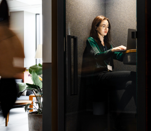 7N female staff member working in a phone booth on her computer